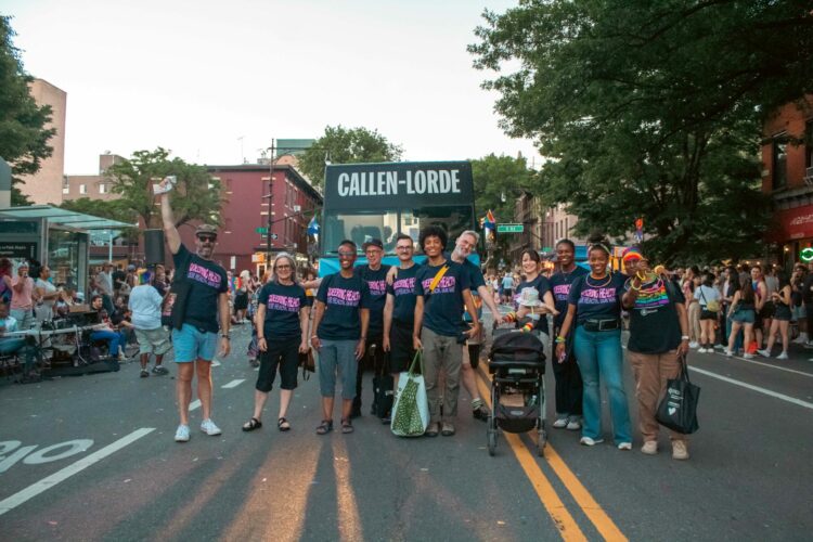 A group of people in Callen Lorde t-shirts march at Pride.